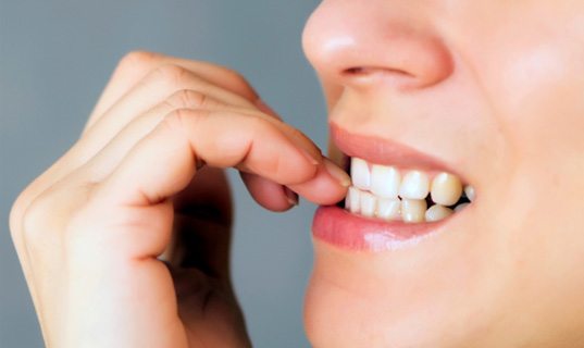 A closeup of a woman biting her fingernails