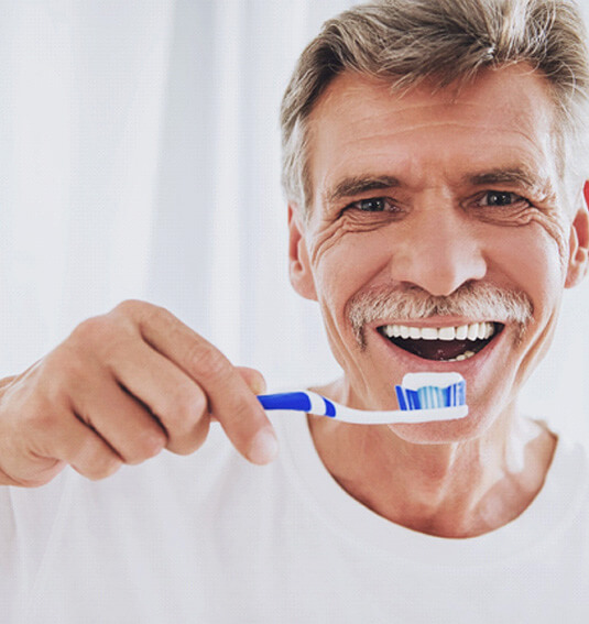 man with dentures holding a toothbrush